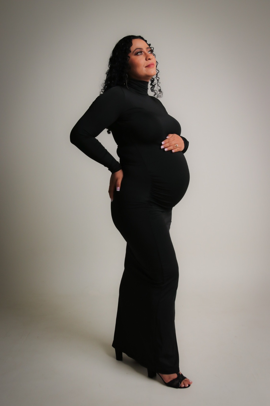 Studio maternity portrait of an expectant mother in a long black dress