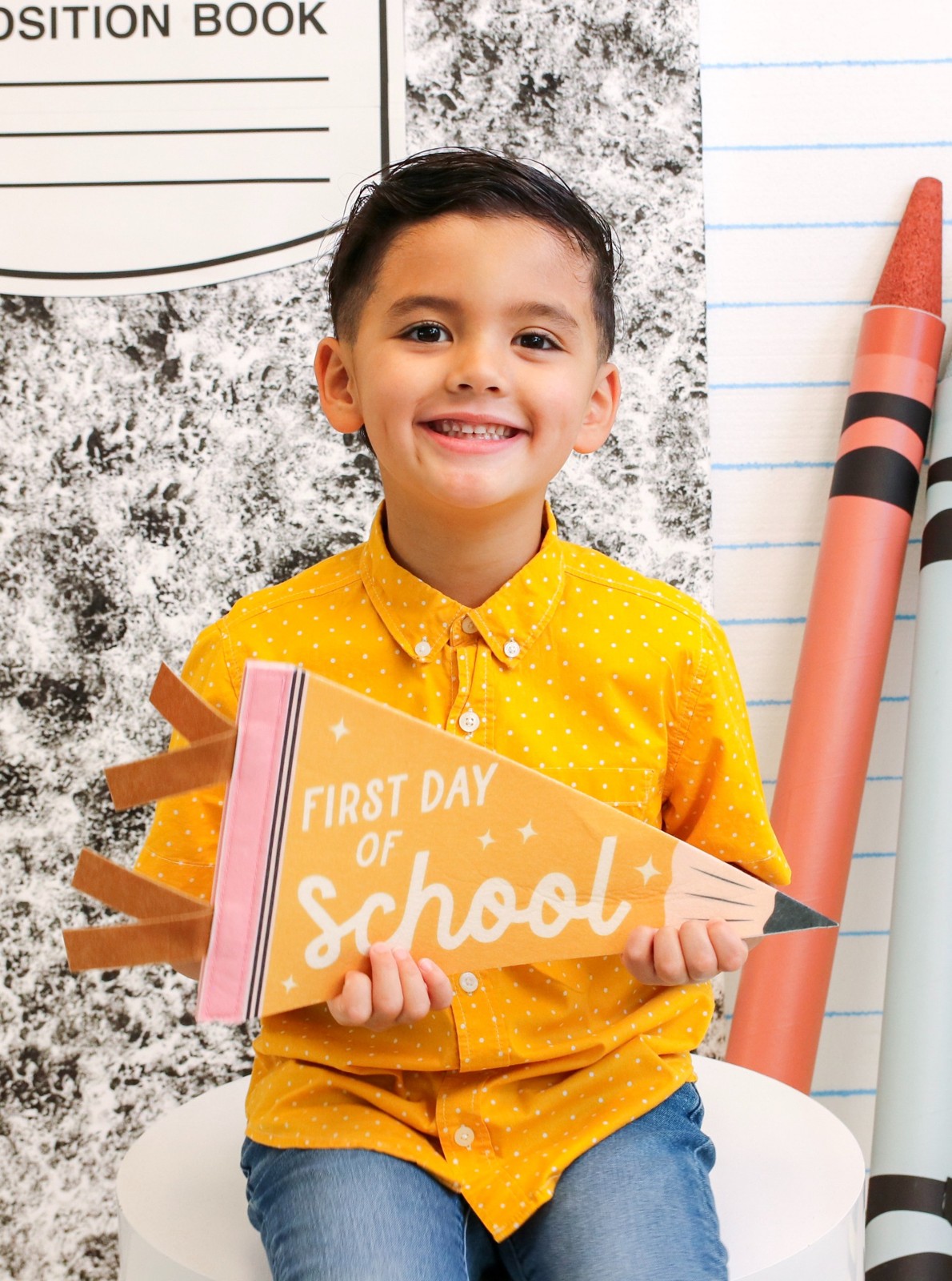 Child celebrating the first day of school with colorful crayon props
