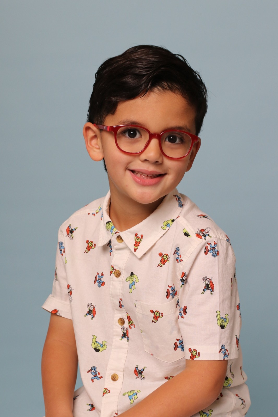 School portrait of a smiling child in red glasses